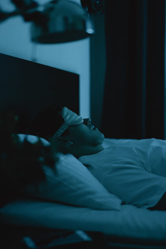 Adult resting peacefully in bed wearing a sleep mask, captured in a serene nighttime setting.
